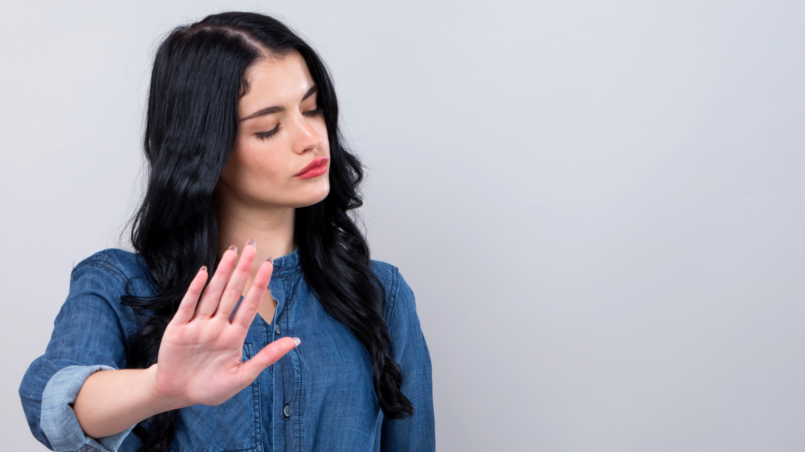 Foto zeigt eine junge Frau mit zurückweisender Hand als Symbol der Ablehnung beim Online-Dating